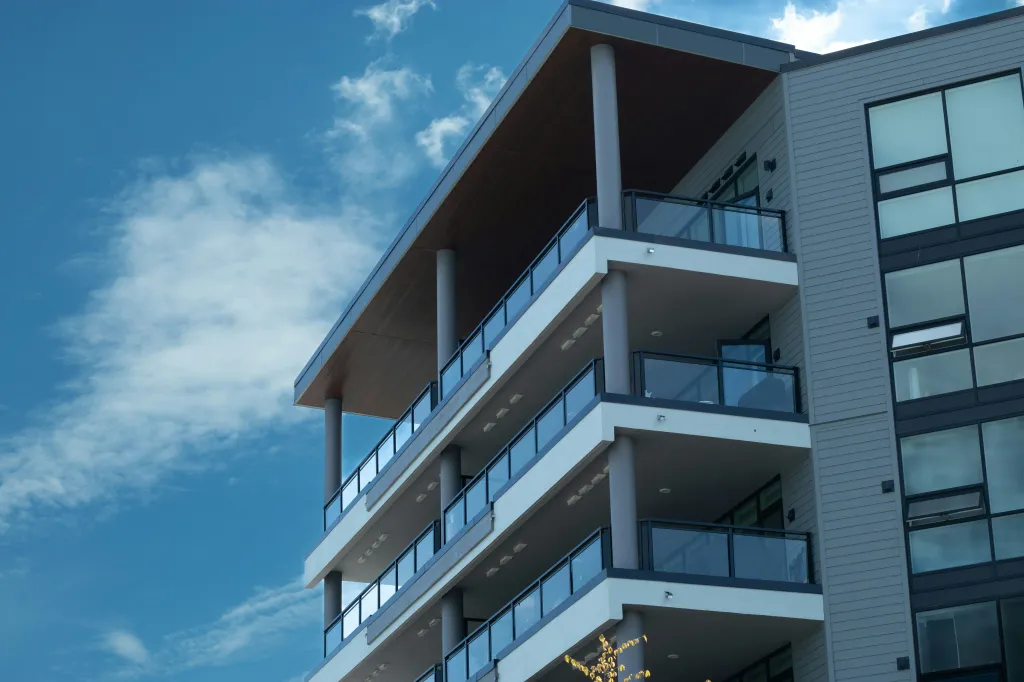 Modern condo building with glass balconies under a blue sky.